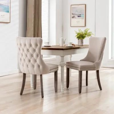 2 Beige Wingback Dining Chairs with Nailhead Trim & Wood Legs